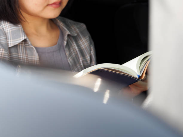 istock Young woman reads a book in the car while parked 2153526995