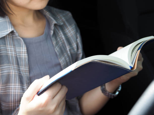 istock Young woman reads a book in the car while parked 2153527001