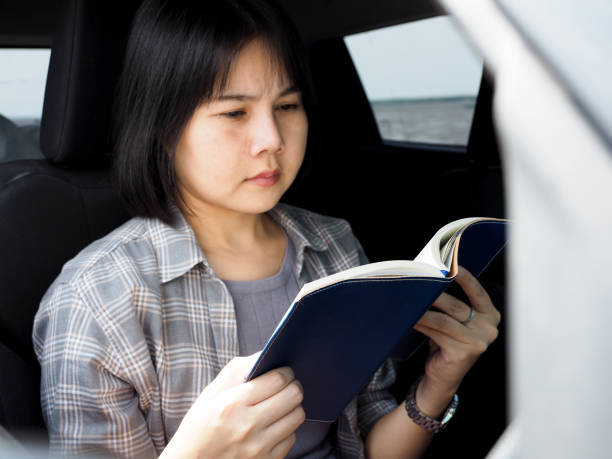 istock Young woman reads a book in the car while parked 2153527092