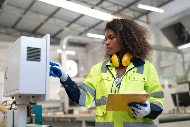 istock African American woman engineer using computer operating CNC machine for cutting wood in furniture factory. Female technical maintenance and programing to machine for making wooden product. 2153528192