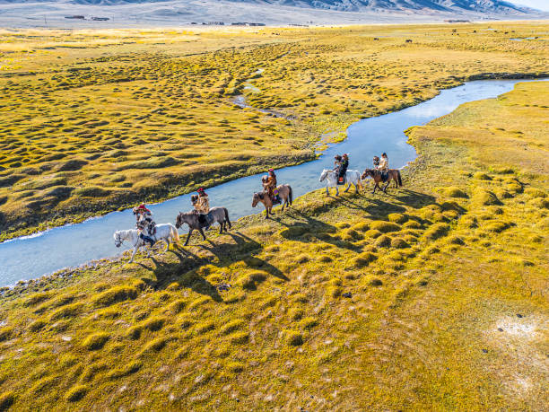 group of Kazakh eagle hunters riding horses along river Bayan Olgii, West Mongolia