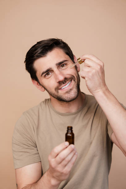 istock Cheerful young man applying organic serum on his face with a dropper 2153544505