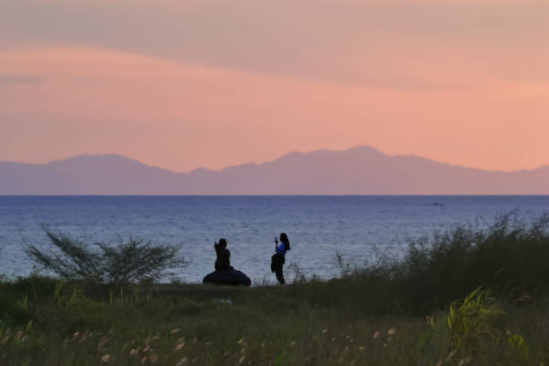 Scenery image of people silhouette at the coast under the dramatic sunset sky