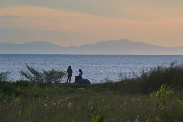Scenery image of people silhouette at the coast under the dramatic sunset sky