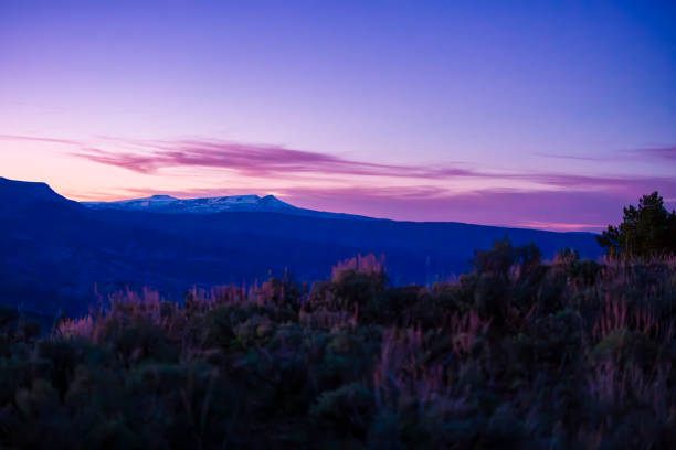 Flat Tops Mountains During Dusk Blue Hour and Scenic Sunset - Landscape of scenic mountain view looking across Sage meadows to distant snowcapped flat mountains with pink and purple sunset skies.