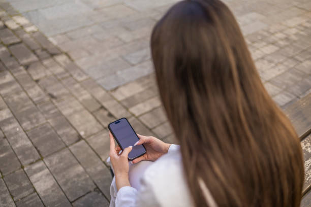 istock Back view of the nurse on the break in white uniform texting a message while sitting on the bench. 2153557692
