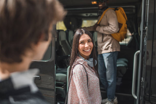 istock A smiling young woman gets into a minibus with her friends 2153564009