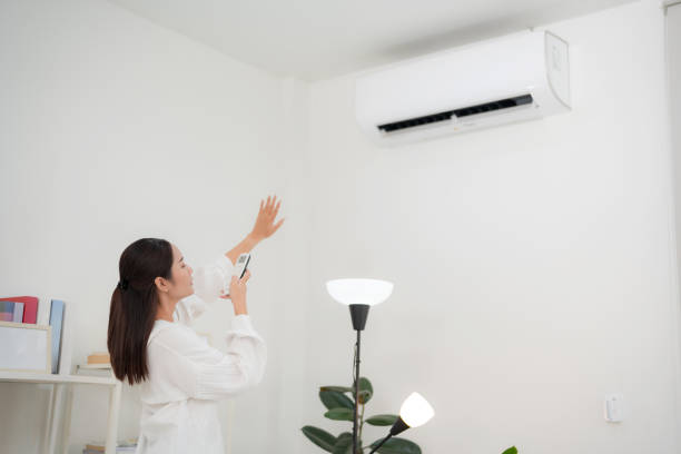 istock Young woman controlling smart air conditioning system at home 2153568876
