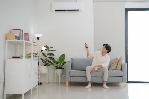 istock Young man enjoying comfort using remote control for air conditioning at home 2153570816