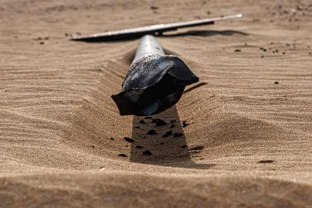 A damaged and broken roundabout road sign, lies in desert sand. No road is visible. Photo taken in the early morning, shortly after sunrise in an area of Dubai known locally as Half Desert Road, or sometimes Half Desert Half Road. It is a road network that has now been mostly taken back by desert sand and sand dunes.