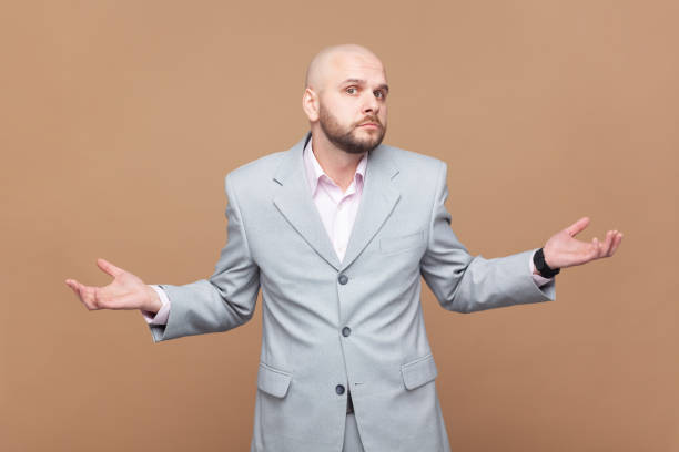 istock Hesitant puzzled bald bearded man shrugs shoulders in bewilderment, looks confusingly at camera. 2153597637
