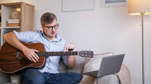 istock Musical school video course man guitar laptop home 2153597770