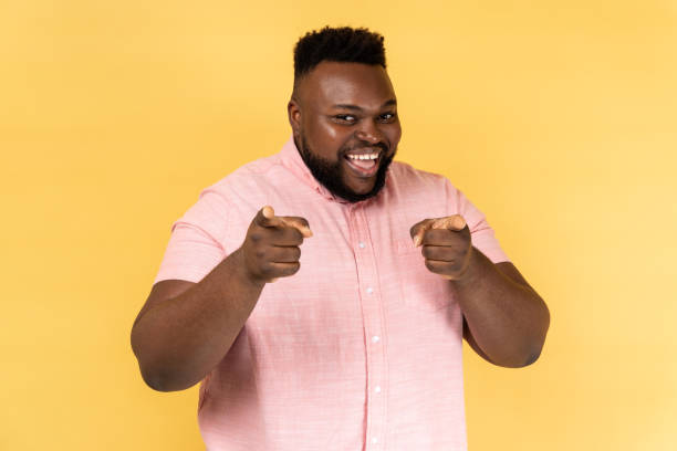 istock Man pointing to camera and looking with charming toothy smile, indicating finger, making choice. 2153598992