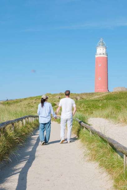 istock Two individuals strolling along a scenic path near a majestic lighthouse in Texel, Netherlands, surrounded by the calming sounds of the ocean 2153603117