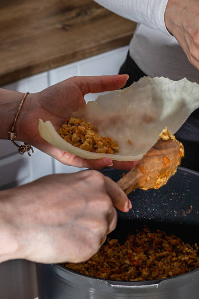 istock A woman cooks cabbage rolls over a pan at home. 2153605931