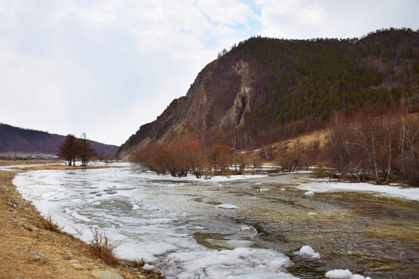 Spring landscape. Buguldeika River near a high mountain in spring, the process of melting ice.
