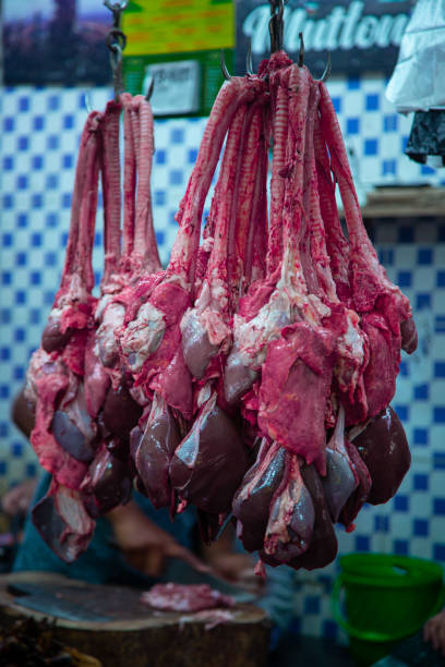 Fresh meat hanging in the shop for sale with blue and white colour wall tiles in the background
