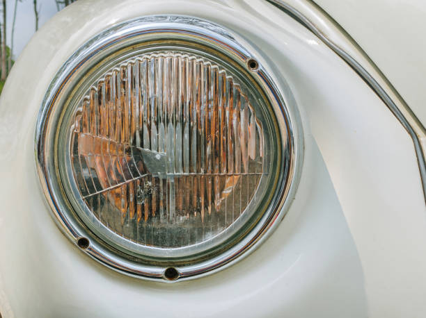 The rounded head lamp of a white vintage car. Close-up.