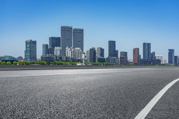 Clean asphalt road with city skyline background.