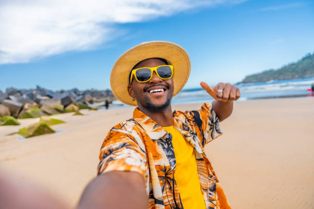 istock African man taking selfie gesturing with thumb up at beach 2153627625