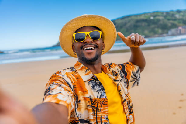 istock African man taking selfie gesturing with thumb up on beach 2153627801