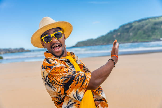 istock Happy afro man in summer clothes pointing a sandy beach 2153627809