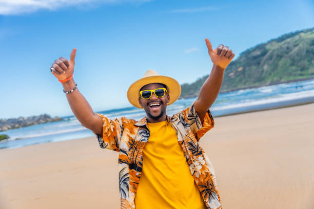 istock Joyful african man raising thumbs and smiling on a beach 2153628337