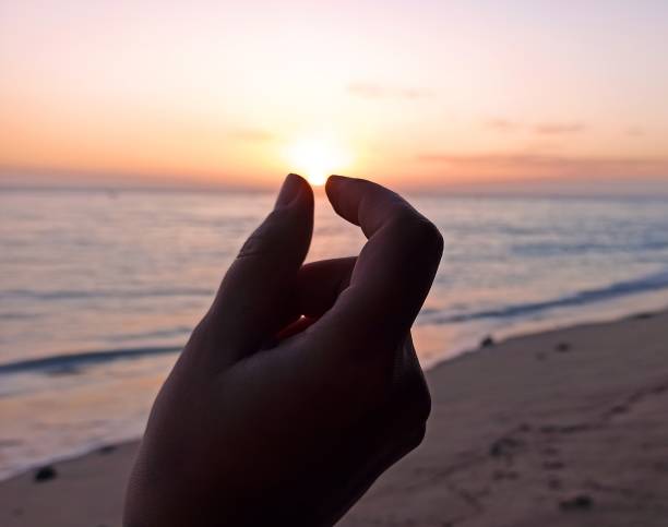 Capturing the sunset on the beach with fingers, feminine hand, in Reunion