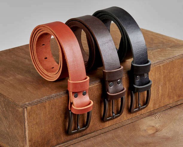 istock Three rolled leather belts of different colors displayed on wooden podium steps 2153634355