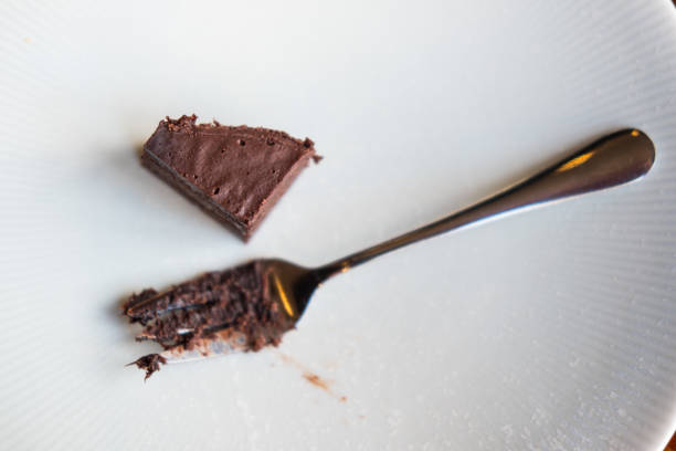 Empty white dirty plate with chocolate cake crumbs and fork after eating