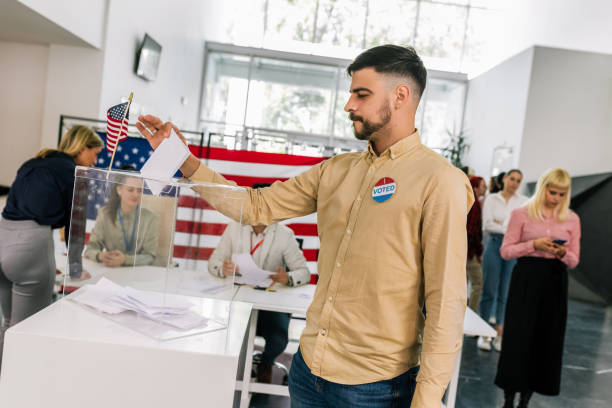 istock Voter placing ballot in ballot box polling place 2153639883