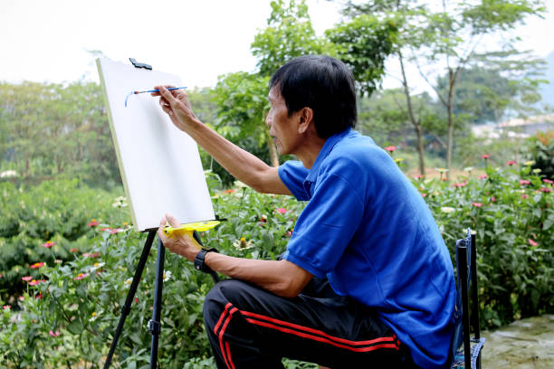 Focused Senior Man Drawing A Line To Make Landscape Painting