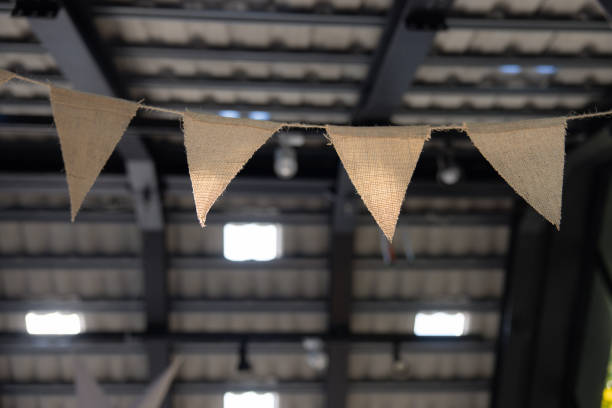 A row of triangle flags hanging from the ceiling. The flags are white and brown. garland flags