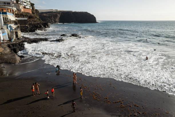 Galdar, Spain, March 29, 2024: People by the sea at bathing facilities during a sunny spring day on March 29, 2024 in Puerto de Sardina, Galdar, Gran Canaria, Canary Islands, Spain.