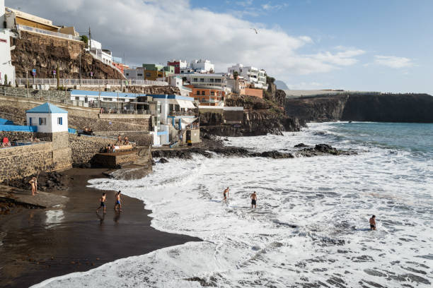 Galdar, Spain, March 29, 2024: People by the sea at bathing facilities during a sunny spring day on March 29, 2024 in Puerto de Sardina, Galdar, Gran Canaria, Canary Islands, Spain.