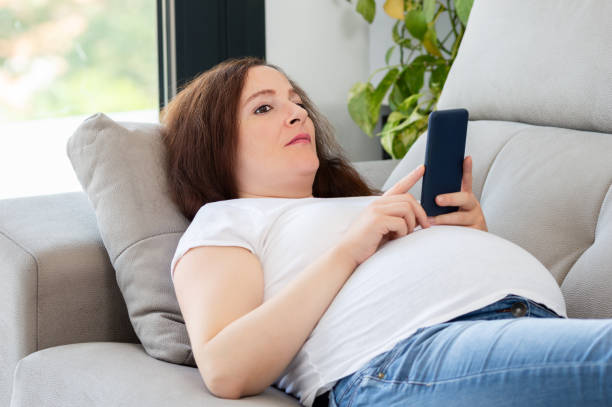 istock pregnant woman lying on couch thinking with mobile phone 2153654884