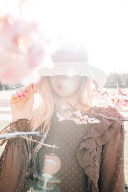 istock Young pretty woman in hat standing in blooming sakura tree 2153656091
