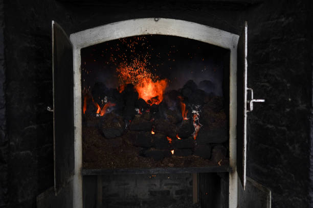 A peat fire in a whisky distillery kiln in Scotland. Peat smoke is used to dry the malted barley. It gives the whisky a distinctive smoky flavour. Peat stock pictures, royalty-free photos & images