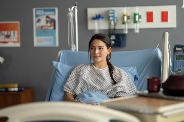Waiting for Surgery A young mixed race woman lays back in her hospital bed as she waits for surgery. She is dressed comfortably in a gown and has a neutral expression on her face. Hospital stock pictures, royalty-free photos & images