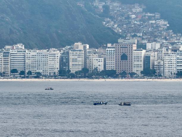 A beach with small fishing boats in the foreground, in Rio de Janeiro, pictured from offshore in the South Atlantic Ocean