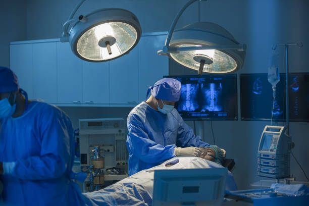 surgeons team working with monitoring of patient in surgical operating room. the doctors and nurses brainstorm power assisted surgery. a team of professional doctors perform surgery in a hospital - anestesista fotografías e imágenes de stock