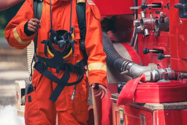 istock Fireman prepare equipment fighting extinguisher at fire engine truck. Firefighter fighting with smoke flame using fire hose, tube, chemical water foam spray at truck. Fireman wear hard hat protection 2153675833