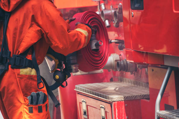 istock Fireman prepare equipment fighting extinguisher at fire engine truck. Firefighter fighting with smoke flame using fire hose, tube, chemical water foam spray at truck. Fireman wear hard hat protection 2153675839