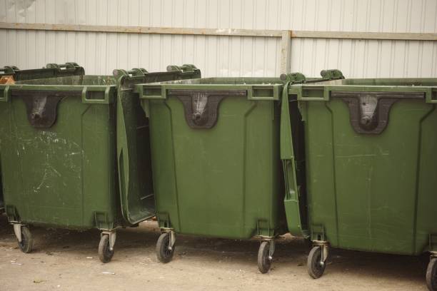 istock Three green dumpsters standing in a row near a metal fence 2153696164