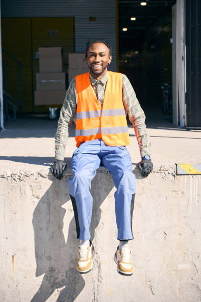istock Loader posing for camera against back entrance to storehouse building 2153700859