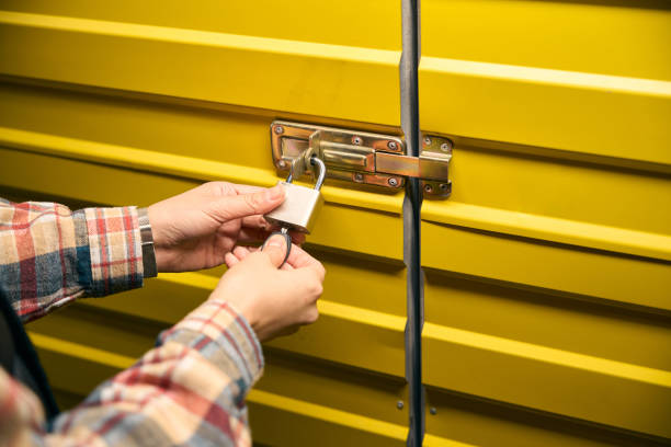 Warehouse worker hands padlocking metal storage unit door
