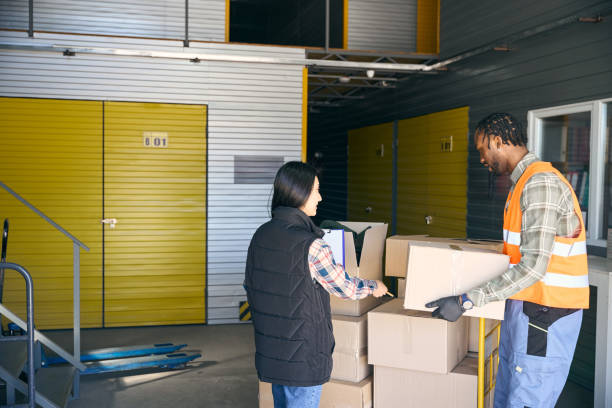 istock Freight handler unloading goods supervised by coworker in storehouse 2153700874