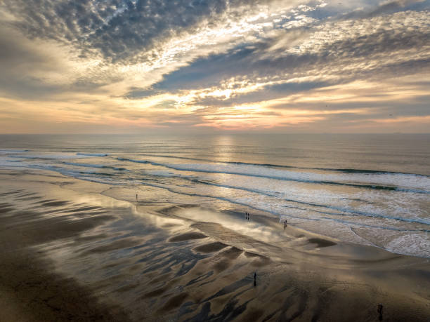 Aerial view of Ocean Beach surf at sunset. Reflections of the sky in the sand.