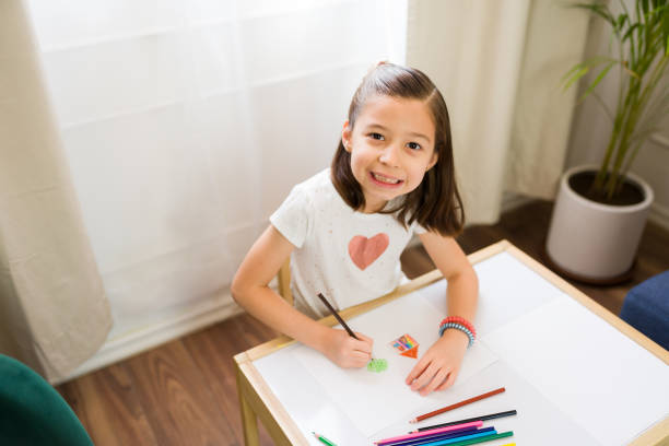 Cheerful little girl participates in a therapy session with colored pencils, signifying a positive approach to child psychology