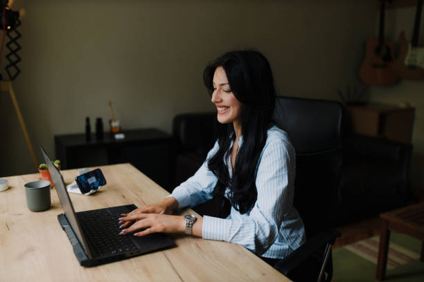 Beautiful young businesswoman sitting in the home office, using a laptop and working from home